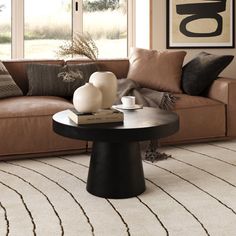 a living room with a brown couch and two white vases on the coffee table