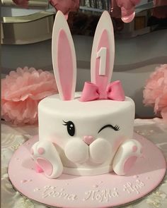 a white cake with pink decorations and bunny ears