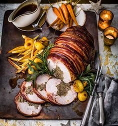 a platter with sliced ham, potatoes and carrots on it next to silverware