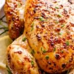 a close up of a chicken on a plate with lemons and parmesan cheese