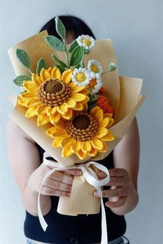 a woman holding a bouquet of sunflowers in her hands