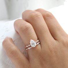 a woman's hand with a diamond ring on her left hand and a white lace napkin in the background