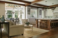 a living room filled with furniture next to a kitchen and dining room table on top of a hard wood floor