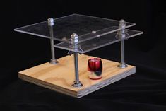 a wooden stand with two red and white vases on it's sides, in front of a black background