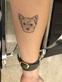 a small dog tattoo on the leg of a person's leg, with a black and white photo behind it