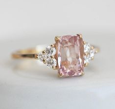 a pink diamond ring with three diamonds around it