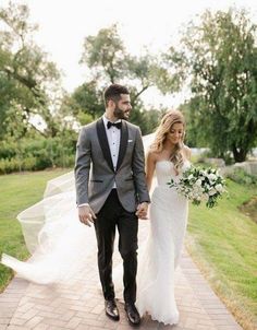 a bride and groom walking down a path holding hands