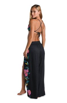 This cover up features a bold floral print with large pink flowers accented by dark and light green leaves. The pattern is set against a dark background, emphasizing the vibrant colors of the flowers and foliage. Perfect for pulling on post dip, the palazzo-style beach pants are perfect as a swimsuit coverup but can also be worn with a tank or cami for a no-fuss pulled together look. An adjustable waist tie finished with gold and black enamel charms offers a comfortable fit. [split] Details Beac Palazzo Style, Swimsuit Material, Split Legs, Bold Floral Print, Pink And Blue Flowers, Dark And Light, Beach Pants, Sun Tan, Enamel Charms