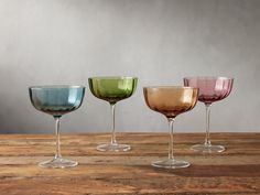 three different colored wine glasses sitting on top of a wooden table next to each other