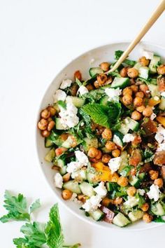 a white bowl filled with chickpeas, cucumber and feta cheese