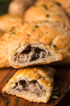 two pastries sitting on top of a wooden cutting board next to mushrooms and parsley