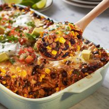 a casserole dish with corn, black beans and avocado on top