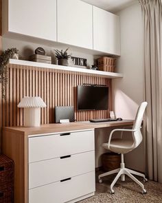 a desk with a computer on top of it next to a white chair and window