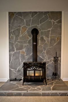 a wood stove sitting in front of a stone wall