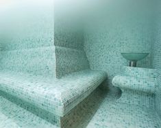 an artistic photo of a bathroom with blue tiles on the walls and stairs leading up to the toilet