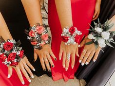 three women in red dresses with flowers on their wrists and one woman's hands