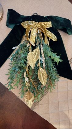 a green velvet bow with gold leaves and beads hanging from it's side on a table