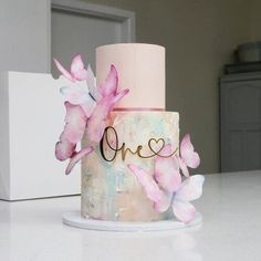 a pink and white cake sitting on top of a table