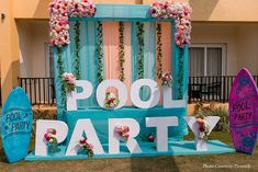 a sign that says pool party with surfboards and flowers on the ground next to it