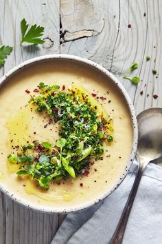 a white bowl filled with soup and garnished with parsley on the side