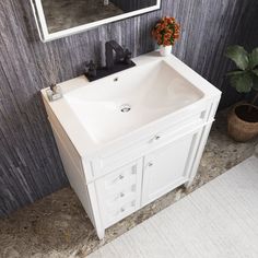 a white sink sitting under a bathroom mirror next to a potted plant on top of a counter