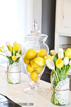 two vases filled with lemons and tulips on a kitchen counter top