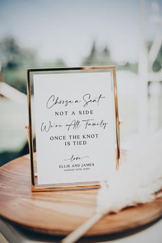 a sign that is sitting on top of a wooden table next to a white feather