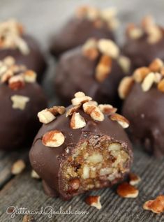 chocolate covered candy with nuts and chopped walnuts on the top, sitting on a wooden surface