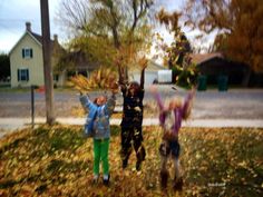 three children are standing in the grass with their hands up