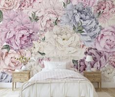 a bed room with a neatly made bed and flowers on the wall