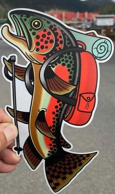 a person holding up a sticker with a fish on it's face and fishing rod