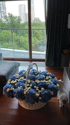 a basket with blue and white flowers in front of a window next to a bed