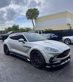 a white sports car parked in a parking lot next to other cars and palm trees