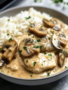 a white plate topped with rice and mushrooms covered in gravy on top of a table