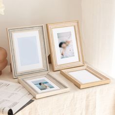 there are three frames on the table and one is holding two pictures, while the other has an open book