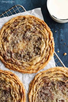 four cookies cooling on a wire rack with a glass of milk in the back ground