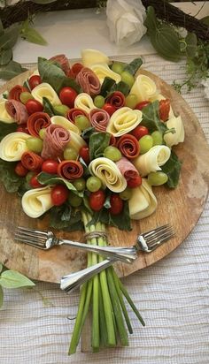 a wooden plate topped with pasta and veggies on top of a white table cloth