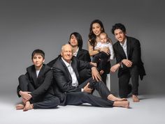 a group of people posing for a photo with one holding a baby and the other sitting down