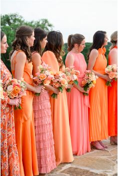 a group of women standing next to each other holding bouquets in their hands and wearing orange dresses