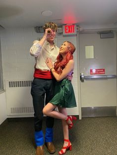 a man and woman dressed up in costume posing for a photo inside an exit sign