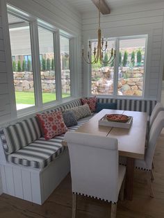 a dining room table and bench in front of windows