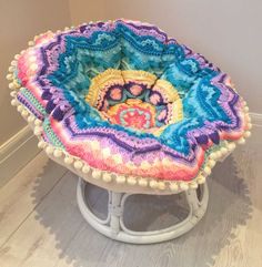 a multicolored crocheted stool with pom - poms on it