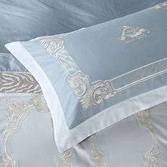 a bed with blue and white comforters on top of it, next to a pillow