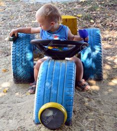 a little boy sitting on top of two blue tires