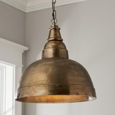 an antique brass pendant light hanging from a ceiling in a room with white walls and windows