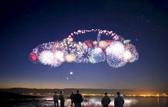 fireworks are lit up in the night sky above people looking out at water and land