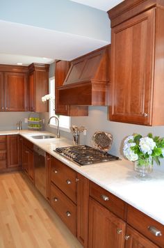 a kitchen with wooden cabinets and white counter tops in the middle of it is shown