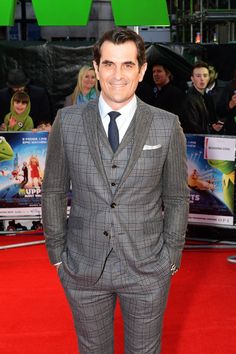 a man in a suit and tie standing on a red carpet at the uk premiere