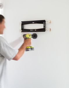 a man is using a paint roller to fix a television wall mounted on the wall