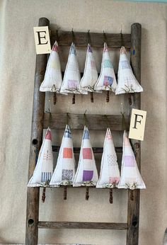 several sailboats are hanging on a wooden ladder and some letters are placed on the wall